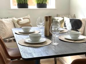 a dining table with plates and wine glasses on it at The Bungalow By Birch Stays in Pentraeth