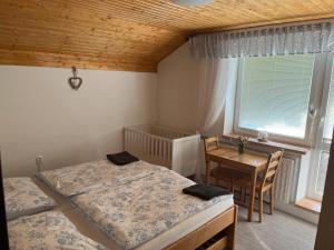 1 dormitorio con 2 camas, mesa y ventana en Chalupa pod Pustevnami, en Trojanovice