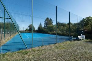 a tennis court with a net on a tennis court at Hotel L'Ecrin 88 Vosges in Grandvillers