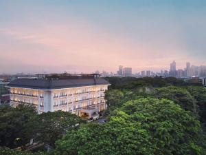 a building with trees in front of a city at The Grand Mansion Menteng by The Crest Collection in Jakarta