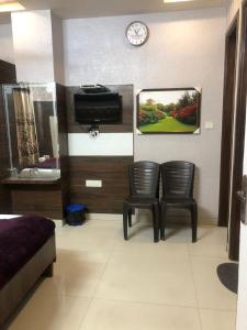 a room with two chairs and a tv on a wall at Hotel Robin Inn in Amritsar