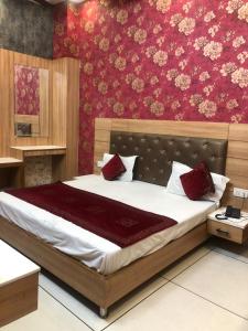 a bedroom with a large bed with red wallpaper at Hotel Robin Inn in Amritsar