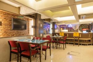 a restaurant with tables and chairs and a tv on the wall at Hotel Kalinga in Indore