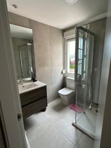 La salle de bains est pourvue de toilettes, d'un lavabo et d'une douche. dans l'établissement El Faro de la Barquera, à San Vicente de la Barquera