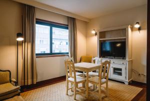 a living room with a table and chairs and a television at Real Residência - Apartamentos Turísticos in Lisbon