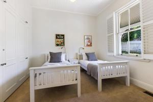 um quarto branco com 2 camas e uma janela em Hatton Ville Fireplace Village 5 Minutes Gardens em Leura