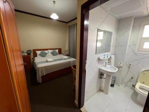 a bathroom with a bed and a toilet and a sink at Al Jazeerah Hotel in Sharjah