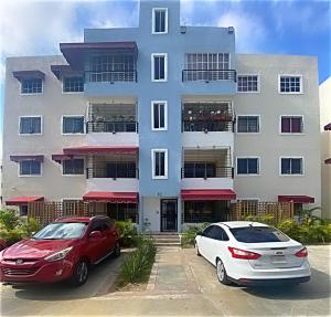 zwei Autos auf einem Parkplatz vor einem Gebäude geparkt in der Unterkunft Casa Apartamento Valentina in Santo Domingo