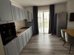 a kitchen with white cabinets and a table and a refrigerator at Serenity Haven Retreat in Floreşti