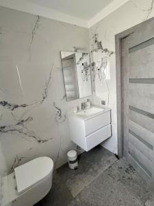 a white bathroom with a toilet and a sink at Serenity Haven Retreat in Floreşti