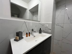 Baño blanco con lavabo y espejo en La Nicchia, en Asti