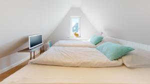 a bedroom with three beds and a television on a table at Beachhouse Beachhouse 5 in Hörnum