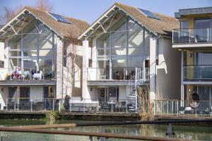 a large house with glass windows and a body of water at Howells Mere 26, Swans Down - P in Somerford Keynes