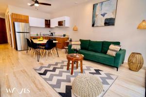 Una sala de estar con un sofá verde y una cocina. en 1 Rec. | Vista a la Jungla + Piscina Infinita + Amenidades LX, en Tulum