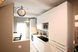 a kitchen with white cabinets and a clock on the wall at Le cosy 40 - maison typique au centre de Malmedy in Malmedy
