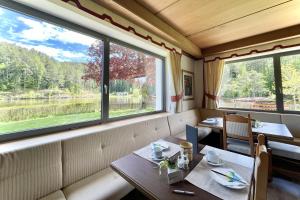 una sala da pranzo con due tavoli e due finestre di Hotel Am Wolfgrubenersee a Soprabolzano