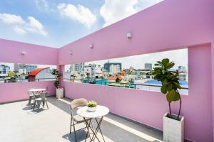 Cette chambre violette dispose d'un balcon avec une table et des chaises. dans l'établissement MeeHOUSE, à Hô-Chi-Minh-Ville