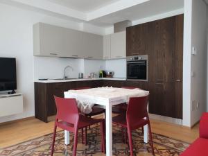 a kitchen with a white table and red chairs at Carboni Paradise Apartment in Cupra Marittima