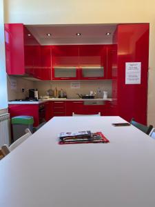 una cocina con armarios rojos y una mesa blanca en Joy Apartment en Sarajevo