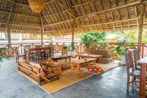 a restaurant with wooden tables and chairs and a thatched roof at La Fontana Zanzibar in Kendwa
