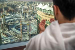 فندق ساعة مكة فيرمونت  في مكة المكرمة: شخص ينظر من النافذة إلى المدينة