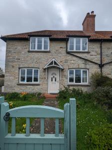 une maison en briques avec un banc bleu devant elle dans l'établissement Cosy family cottage south Somerset, à Long Sutton