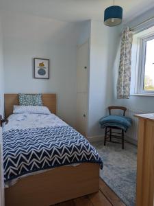 a bedroom with a bed and a chair and a window at Cosy family cottage south Somerset in Long Sutton