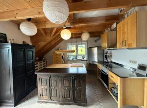 a large kitchen with wooden ceilings and a black island at Panorama-Suite Birkenbeul in Birkenbeul +10 photos