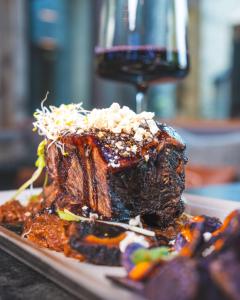 un trozo de carne en un plato con una copa de vino en Stockinggut by AvenidA Hotel & Residences, en Leogang