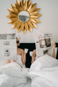 una mujer sentada en la cama leyendo periódicos y bebiendo café en Hubertus Boutiquehotel Filzmoos, en Filzmoos