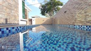a swimming pool with blue tiles on the side of a building at D'ZAHRA HOME - with 30ft private pool in Malacca