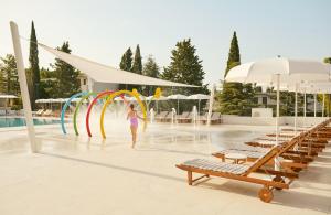 a woman walking in the water at a resort at Bluesun Holiday Village Bonaca - Full Board Plus in Bol +37 photos