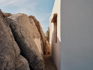 a hallway between two large rocks next to a building at The Wild by Interni in Kalafatis