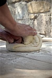 a person kneading a dough on a table at The Wild by Interni in Kalafatis