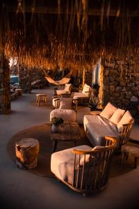 a room with couches and chairs and a stone wall at The Wild by Interni in Kalafatis