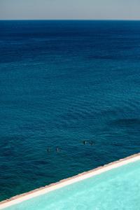 a group of people swimming in the water on a beach at The Wild by Interni in Kalafatis