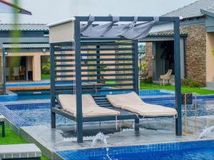 a pergola over a swimming pool with two chairs at The Lux Hotel and Resorts in Louis Trichardt