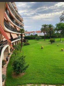 un patio verde con palmeras y un edificio en Apartamento Los Carmenes, playa de Gandia, en Playa de Gandía