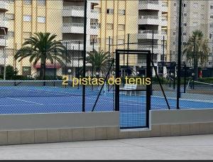 una pista de tenis con red en una pista de tenis en Apartamento Los Carmenes, playa de Gandia, en Playa de Gandía
