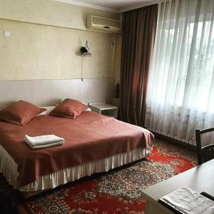 1 dormitorio con 1 cama con manta roja y ventana en Berkana Hotel, en Almaty