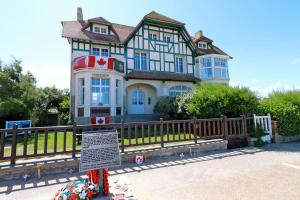 una casa grande con un cartel delante en Maison avec terrasses à 300m de la mer Juno Beach, en Bernières-sur-Mer