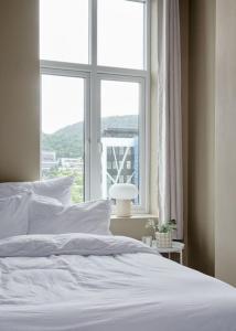sypialnia z białym łóżkiem i oknem w obiekcie Lys & luksuriøs leilighet midt i Bergen sentrum! w Bergen