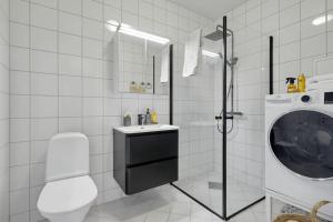 biała łazienka z umywalką i pralką w obiekcie Lys & luksuriøs leilighet midt i Bergen sentrum! w Bergen
