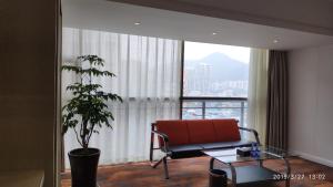 a living room with a chair and a plant in front of a window at Century Hotel Tongren in Tongren