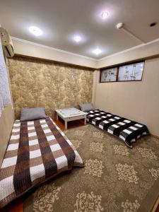 a bedroom with two beds and a table in it at InJoy Hostel in Shymkent
