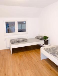 2 Betten in einem weißen Zimmer mit Fenster in der Unterkunft Wohnung Bruchsal in Bruchsal