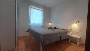 a bedroom with a bed and a window at Apartments Lucija-Klara in Brodarica