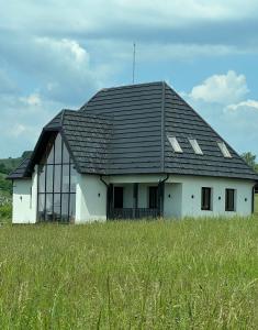 a white house with a black roof in a field at arra housing near Bistrita in Şintereag