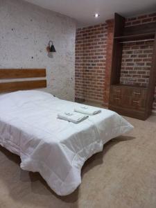 a bedroom with a white bed with two towels on it at Quinta Alpaca in Arequipa