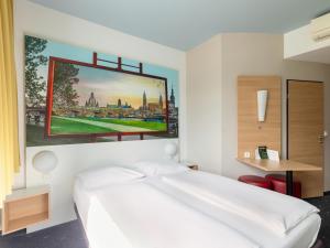 een slaapkamer met een wit bed en een schilderij aan de muur bij B&B Hotel Dresden in Dresden